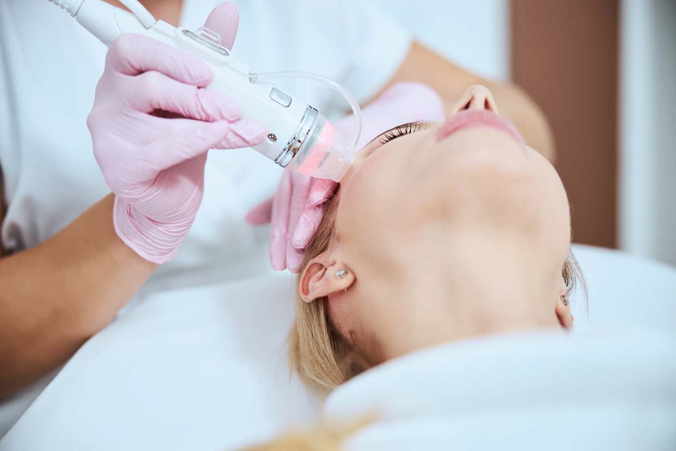Cosmetologist treating her patient with a microneedle beauty machine